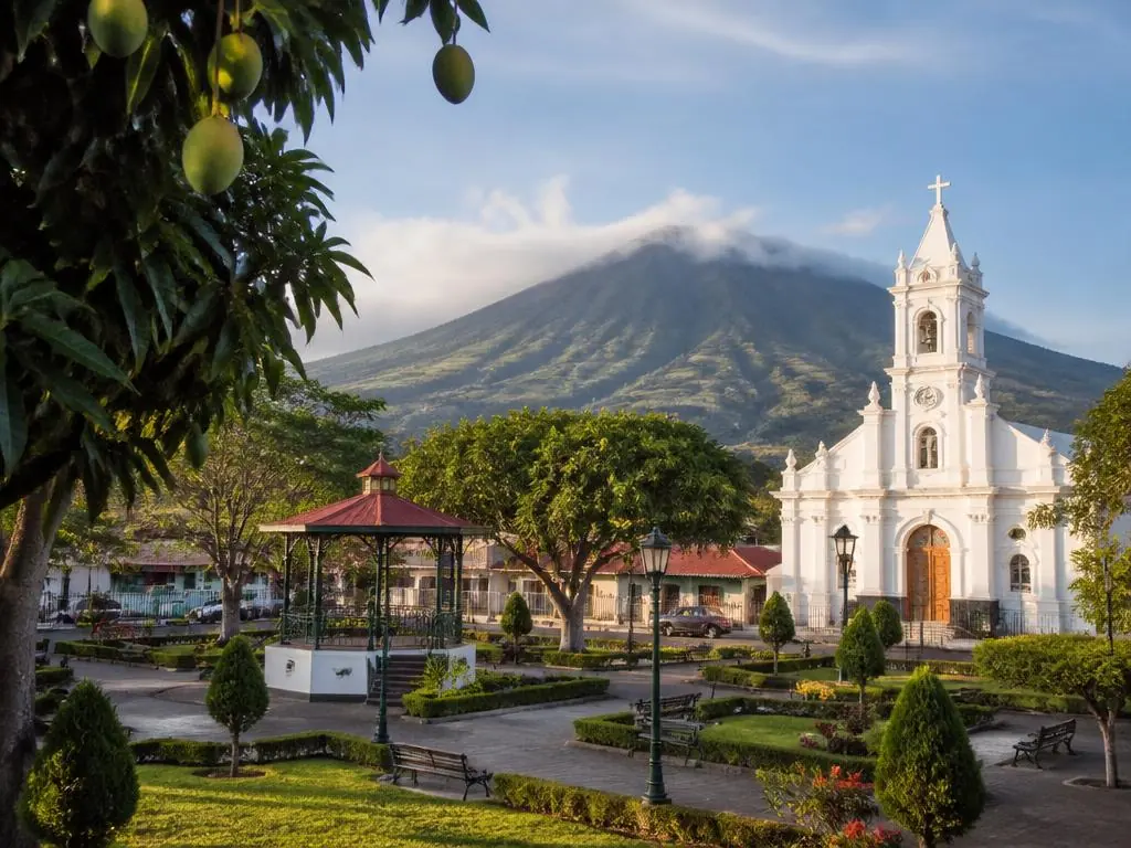 Colonial plaza in Alajuela with coffee-covered volcano slopes beyond